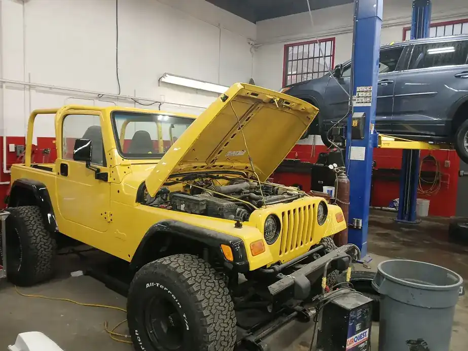 A yellow Jeep in the bay with the hood up
